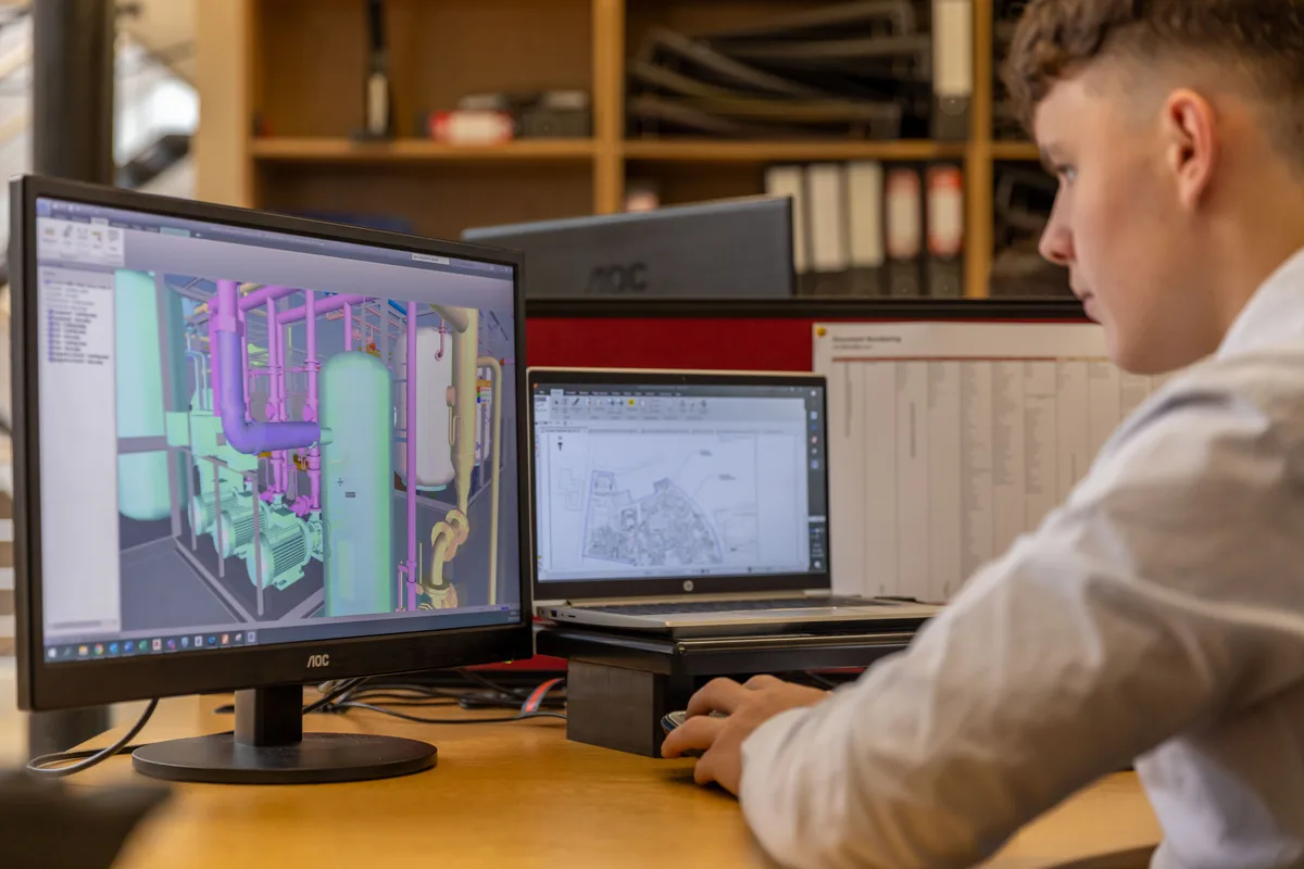 Mérnök két monitoron egy ipari csővezeték-rendszer 3D CAD-modelljét vizsgálja