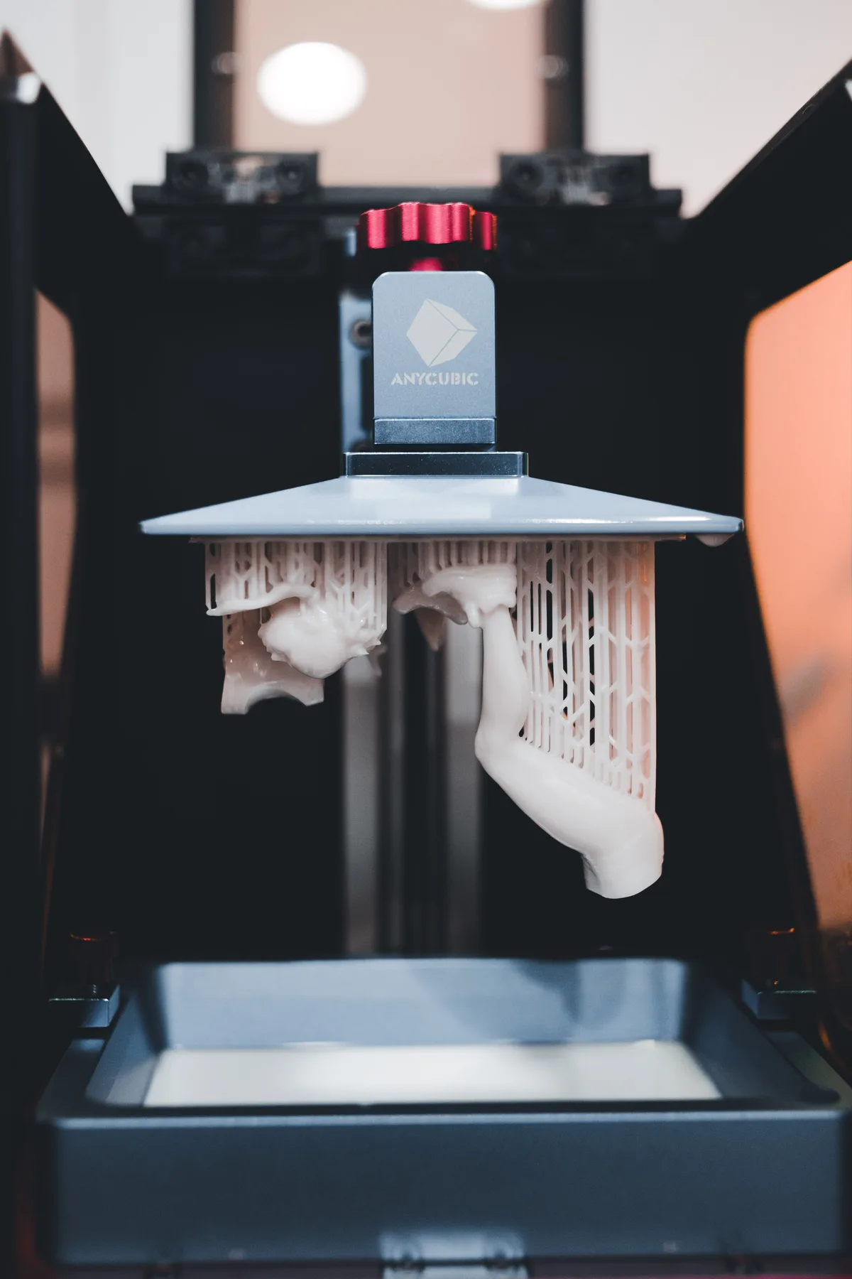 MSLA 3D nyomtató build platformja a gyantás tartályból kiemelve, két alkatrész még rács alakú (lattice) support szerkezeten függ